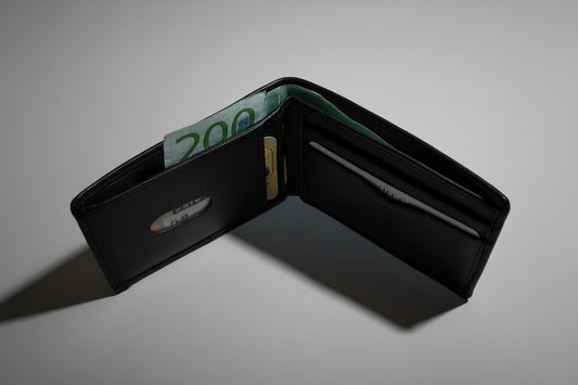 Black wallet with a 200 kr bill inside on a gray background